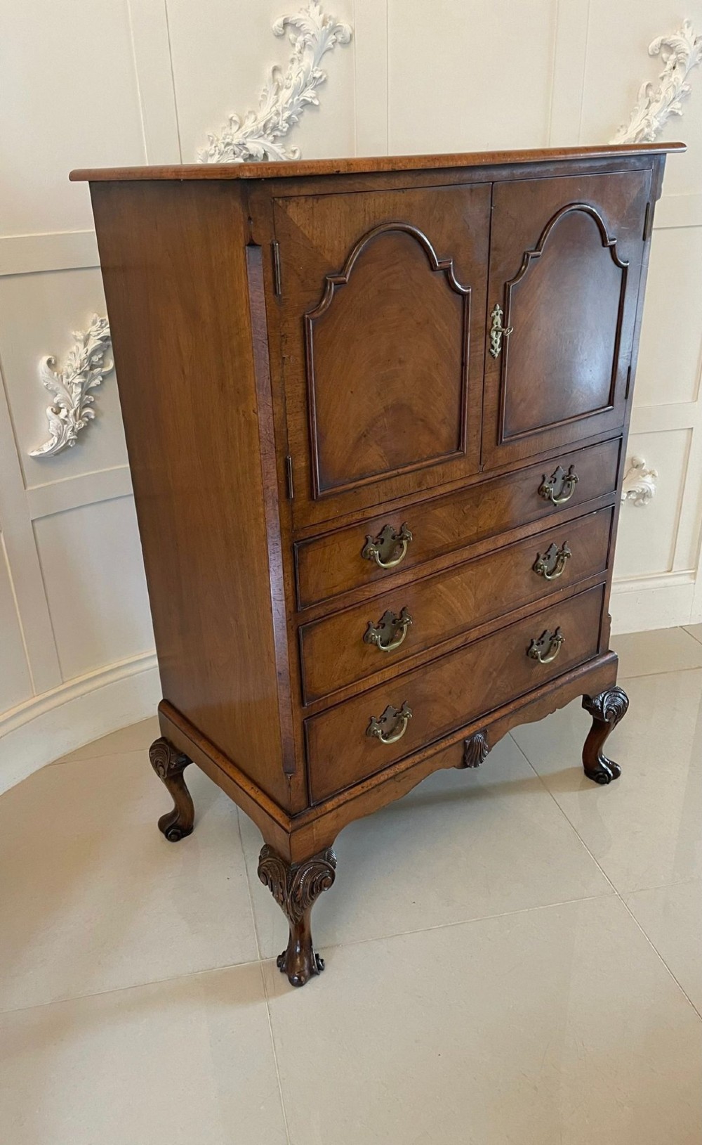 An antique burr walnut chest on stand featuring a two-door cupboard with arched panels above three long drawers, resting on carved cabriole legs. View VII