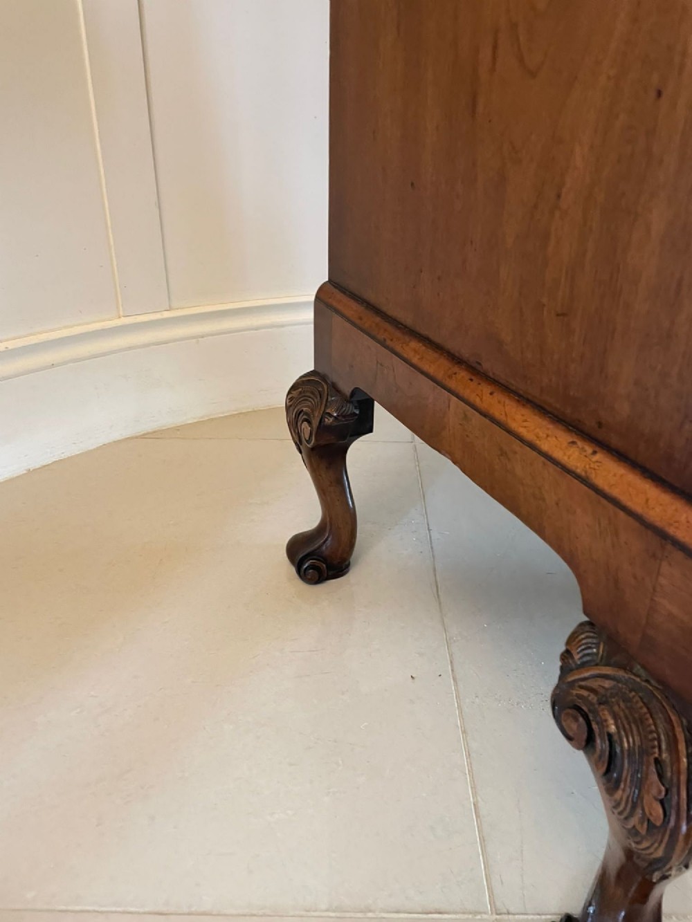 An antique burr walnut chest on stand featuring a two-door cupboard with arched panels above three long drawers, resting on carved cabriole legs. View IX