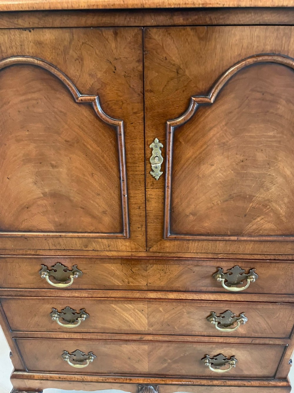 An antique burr walnut chest on stand featuring a two-door cupboard with arched panels above three long drawers, resting on carved cabriole legs. View X