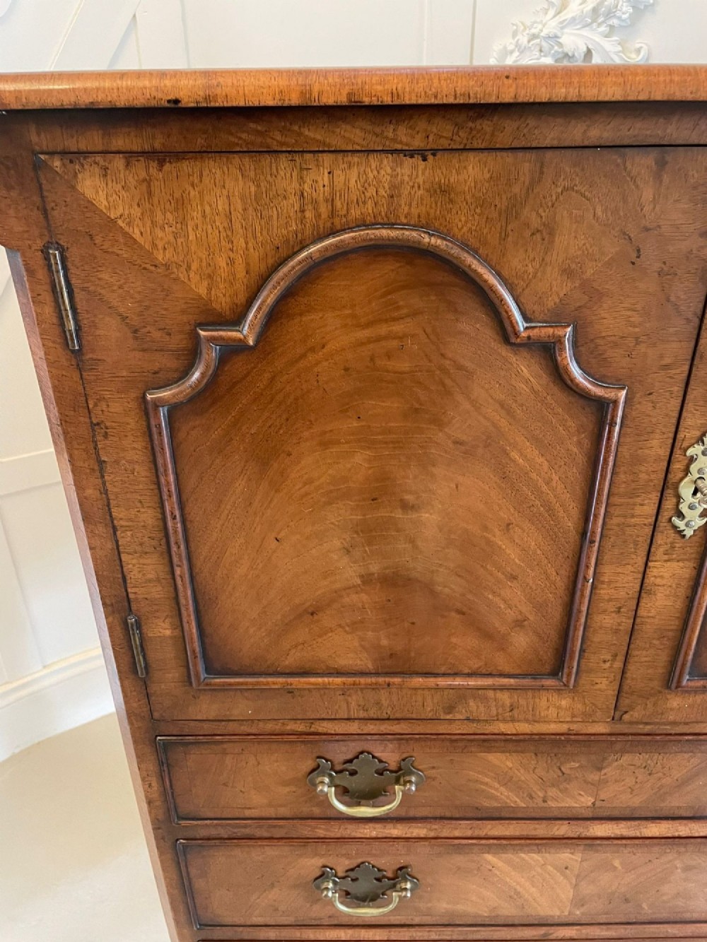 An antique burr walnut chest on stand featuring a two-door cupboard with arched panels above three long drawers, resting on carved cabriole legs. View XI
