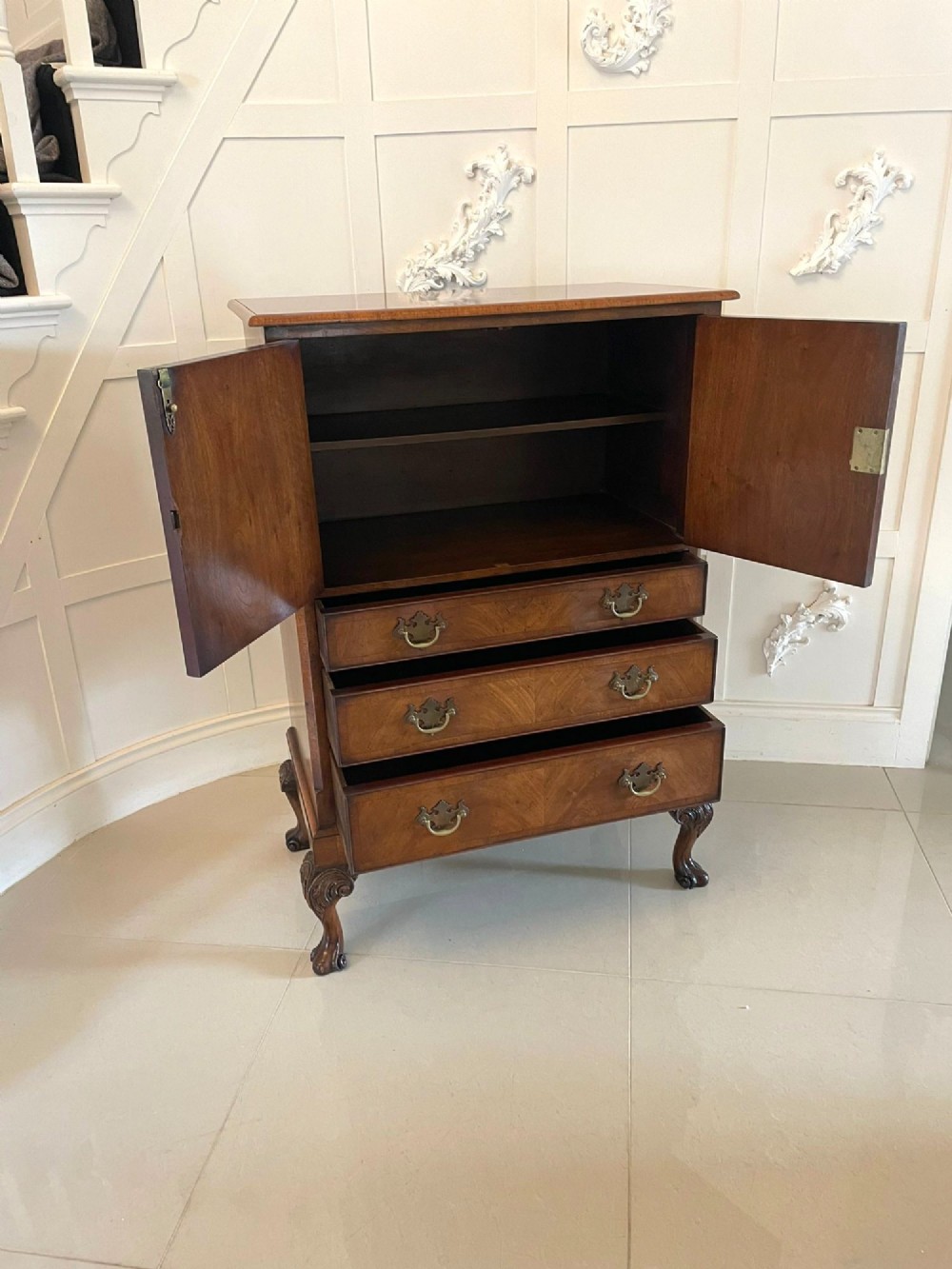 An antique burr walnut chest on stand featuring a two-door cupboard with arched panels above three long drawers, resting on carved cabriole legs. View XIII