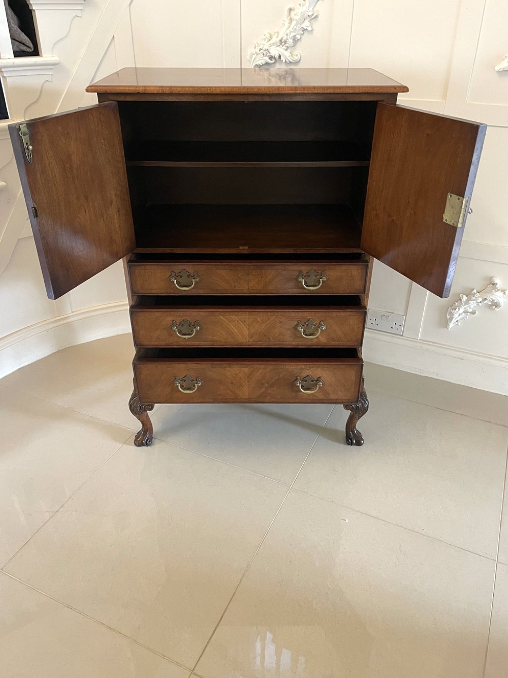 An antique burr walnut chest on stand featuring a two-door cupboard with arched panels above three long drawers, resting on carved cabriole legs. View XIV