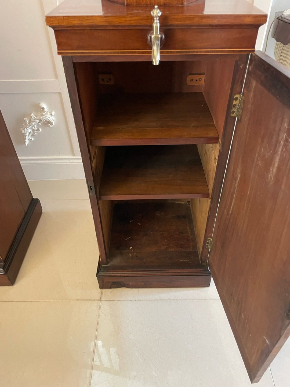A pair of George III mahogany wine urns featuring flame mahogany oval inlay panels resting atop matching square pedestal cupboards with brass spigots. View II