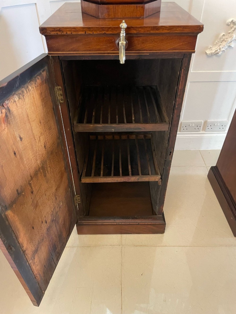 A pair of George III mahogany wine urns featuring flame mahogany oval inlay panels resting atop matching square pedestal cupboards with brass spigots. View IV