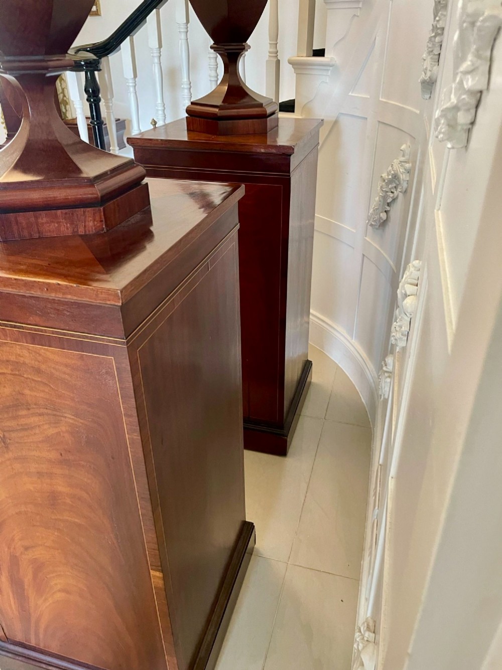 A pair of George III mahogany wine urns featuring flame mahogany oval inlay panels resting atop matching square pedestal cupboards with brass spigots. View VIII