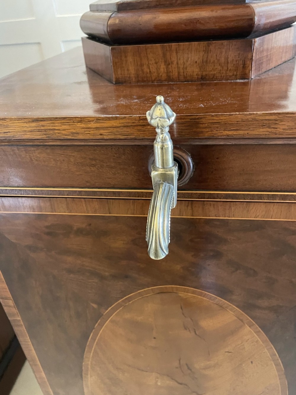 A pair of George III mahogany wine urns featuring flame mahogany oval inlay panels resting atop matching square pedestal cupboards with brass spigots. View X