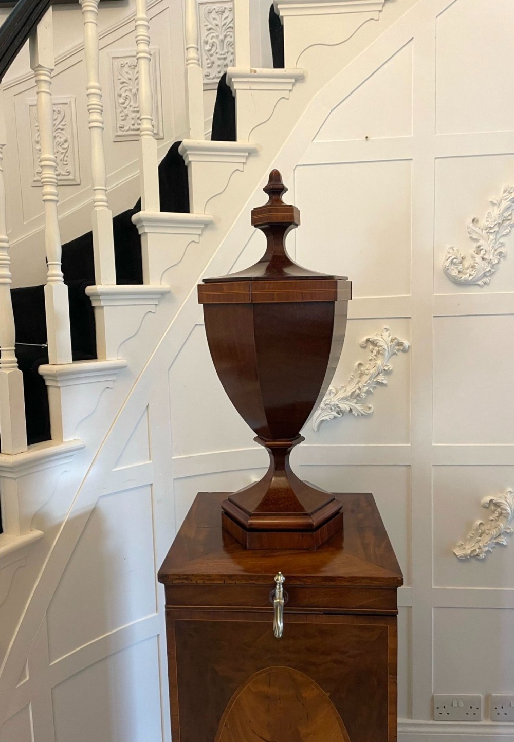 A pair of George III mahogany wine urns featuring flame mahogany oval inlay panels resting atop matching square pedestal cupboards with brass spigots. View XII