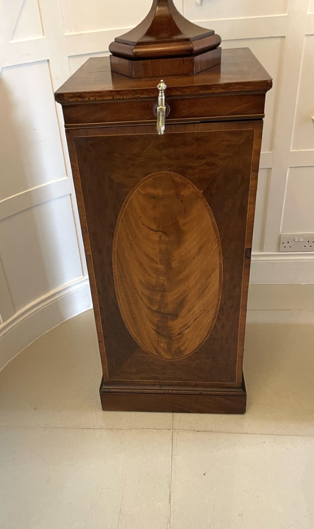 A pair of George III mahogany wine urns featuring flame mahogany oval inlay panels resting atop matching square pedestal cupboards with brass spigots. View XIV