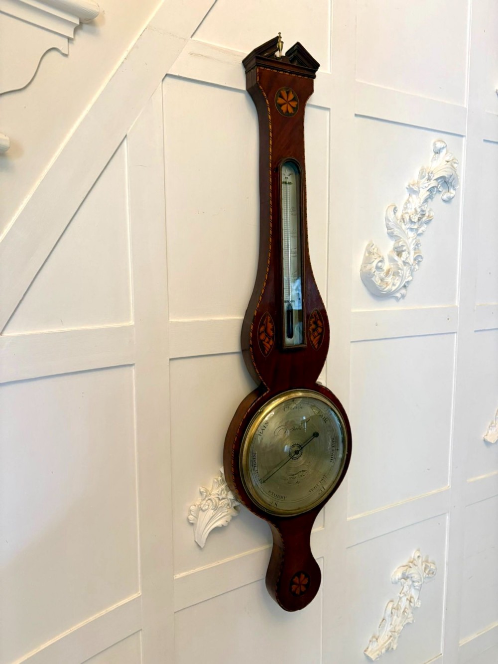 An antique George III mahogany banjo wall barometer featuring shell marquetry inlays, a silvered circular dial, an integrated mercury thermometer, and a broken-arch pediment with a brass finial. View IV