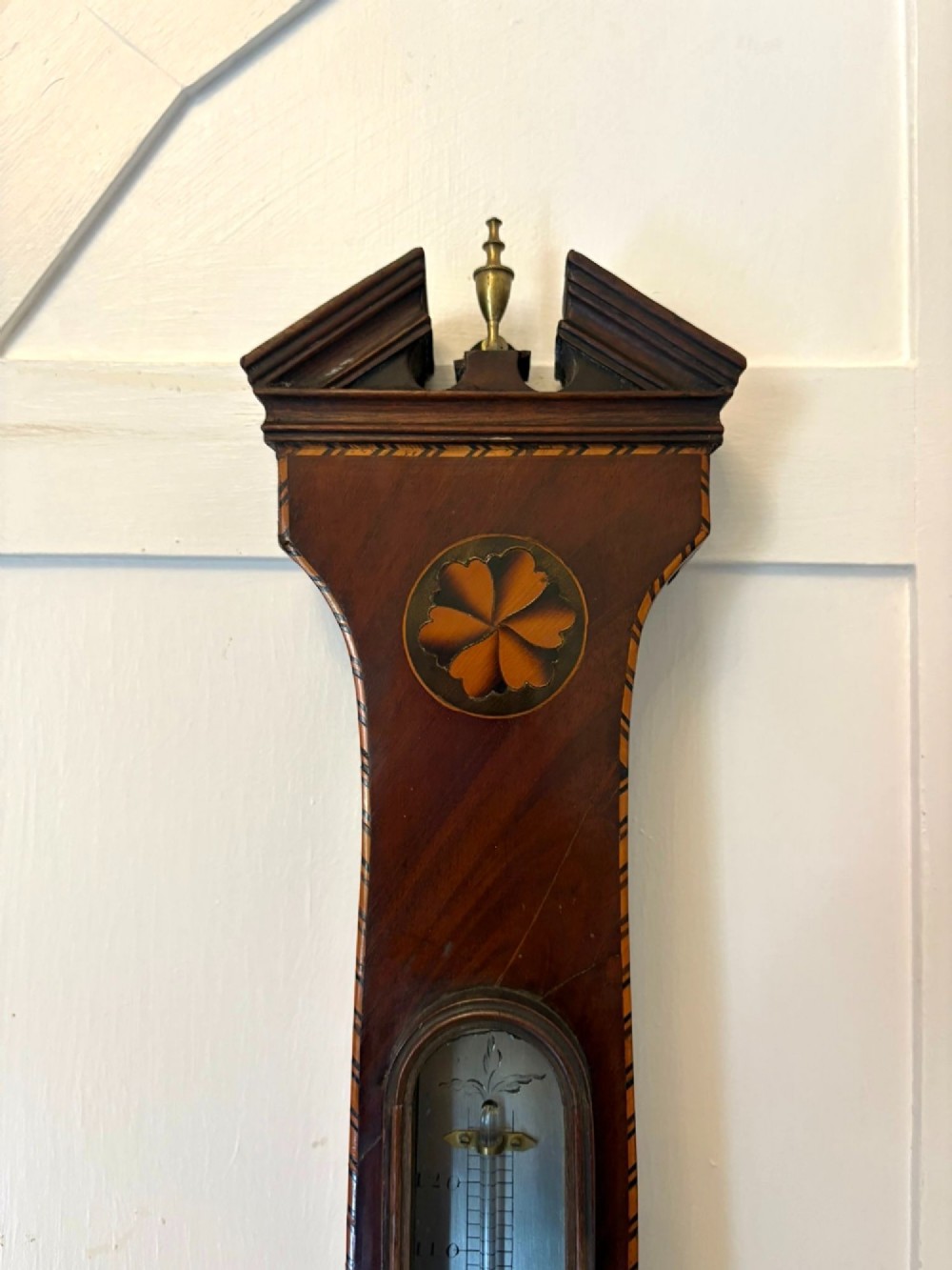 An antique George III mahogany banjo wall barometer featuring shell marquetry inlays, a silvered circular dial, an integrated mercury thermometer, and a broken-arch pediment with a brass finial. View V