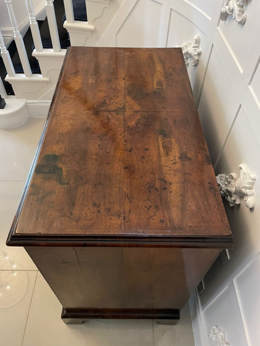 A George I period chest of drawers in figured walnut featuring two short drawers over three long drawers with brass drop handles and bracket feet. View V