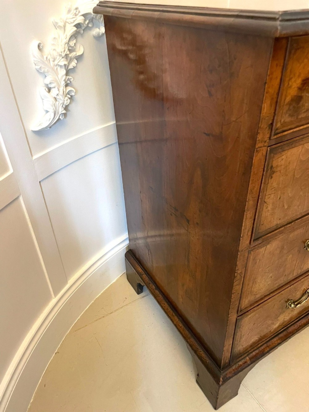 A George I period chest of drawers in figured walnut featuring two short drawers over three long drawers with brass drop handles and bracket feet. View X