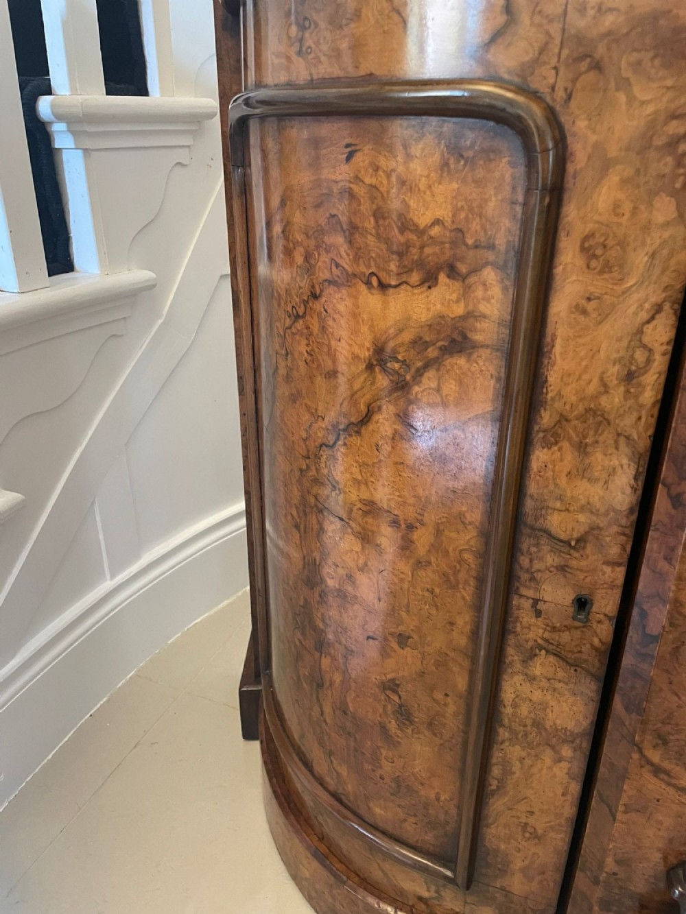 A Victorian burr walnut credenza featuring a serpentine white marble top, mirrored cupboard doors, and a large oval mirror back with carved scrolling detail. View XII