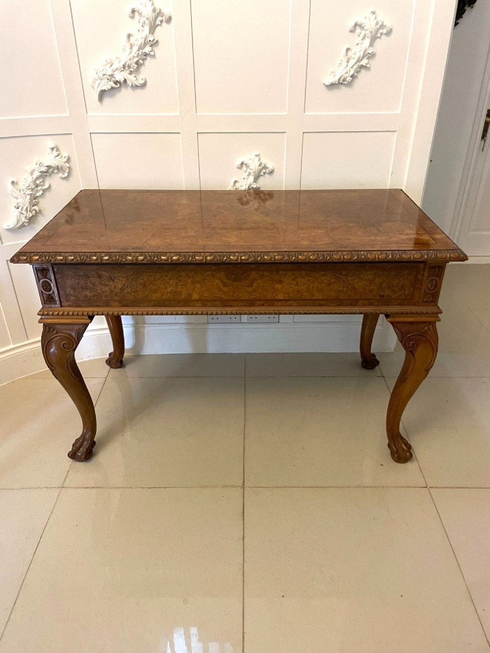 An antique burr walnut console table featuring two drawers, intricate carved moulding along the frame, and carved cabriole legs ending in claw feet. View III