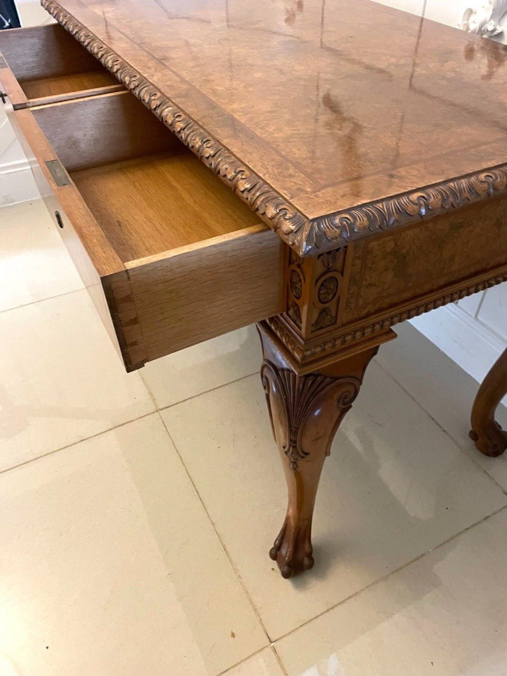 An antique burr walnut console table featuring two drawers, intricate carved moulding along the frame, and carved cabriole legs ending in claw feet. View IV