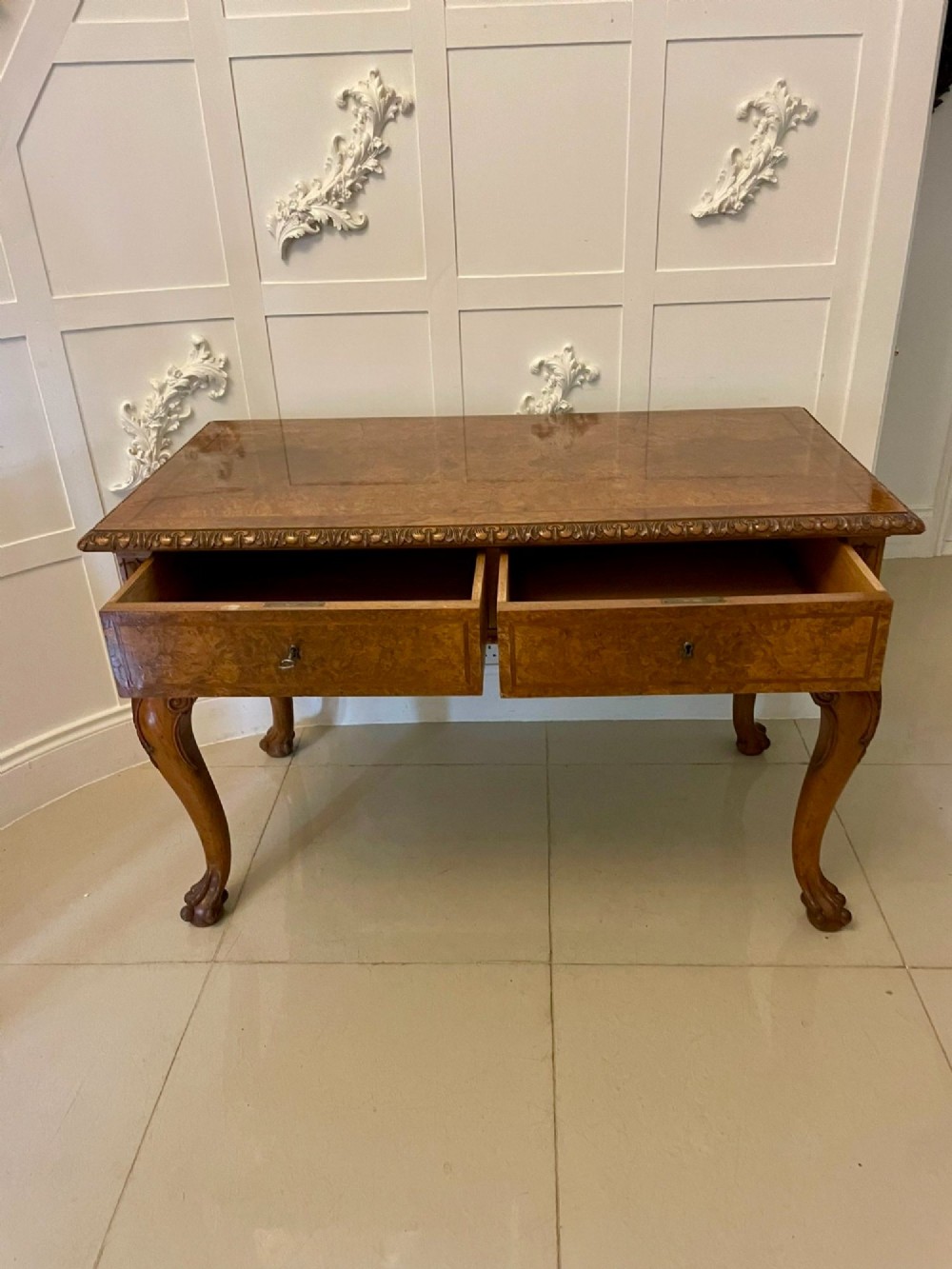 An antique burr walnut console table featuring two drawers, intricate carved moulding along the frame, and carved cabriole legs ending in claw feet. View V