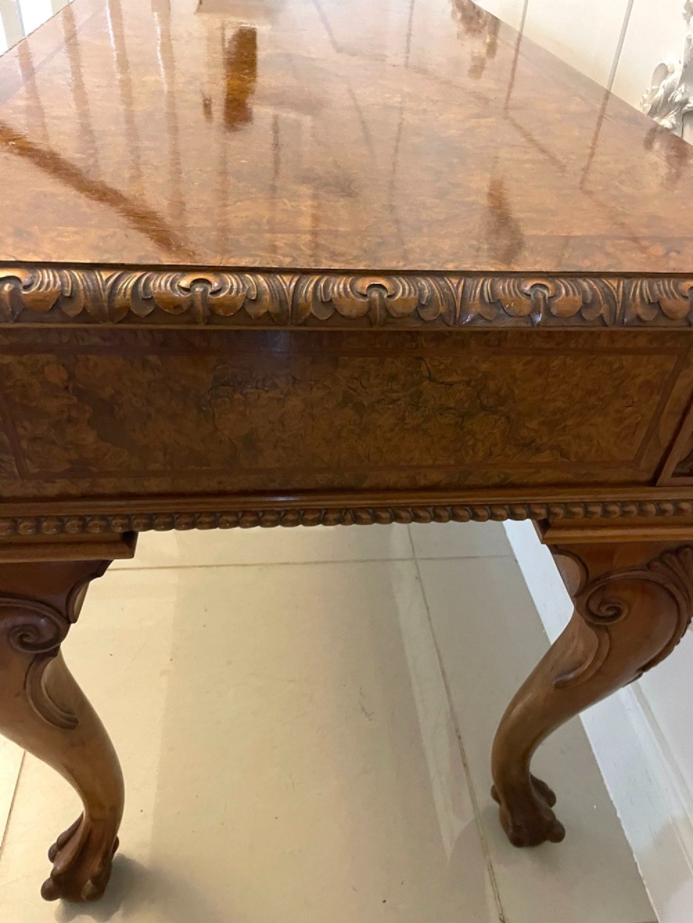 An antique burr walnut console table featuring two drawers, intricate carved moulding along the frame, and carved cabriole legs ending in claw feet. View VII