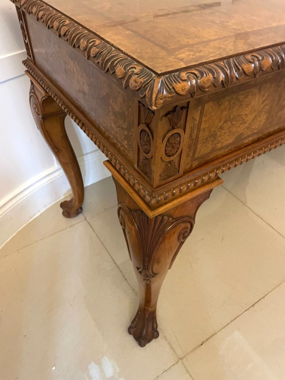 An antique burr walnut console table featuring two drawers, intricate carved moulding along the frame, and carved cabriole legs ending in claw feet. View VIII