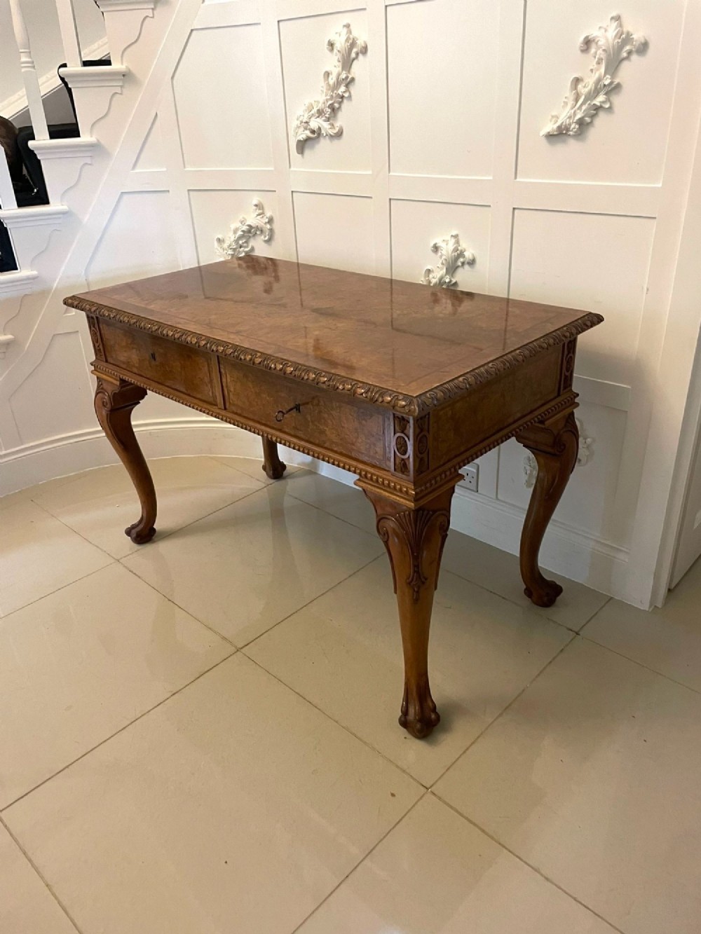 An antique burr walnut console table featuring two drawers, intricate carved moulding along the frame, and carved cabriole legs ending in claw feet. View XIV