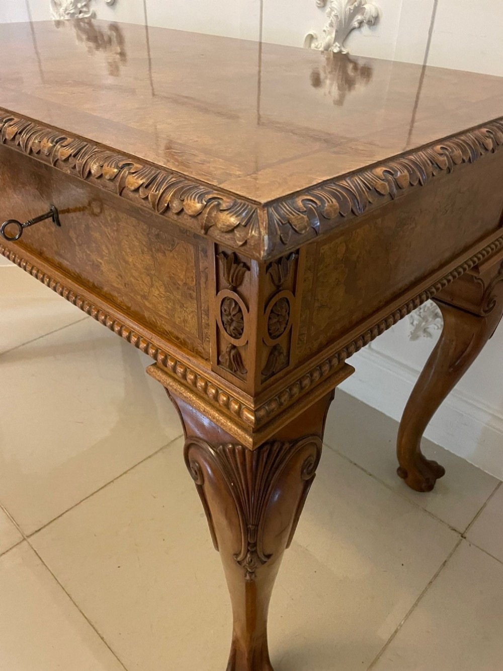 An antique burr walnut console table featuring two drawers, intricate carved moulding along the frame, and carved cabriole legs ending in claw feet. View XV