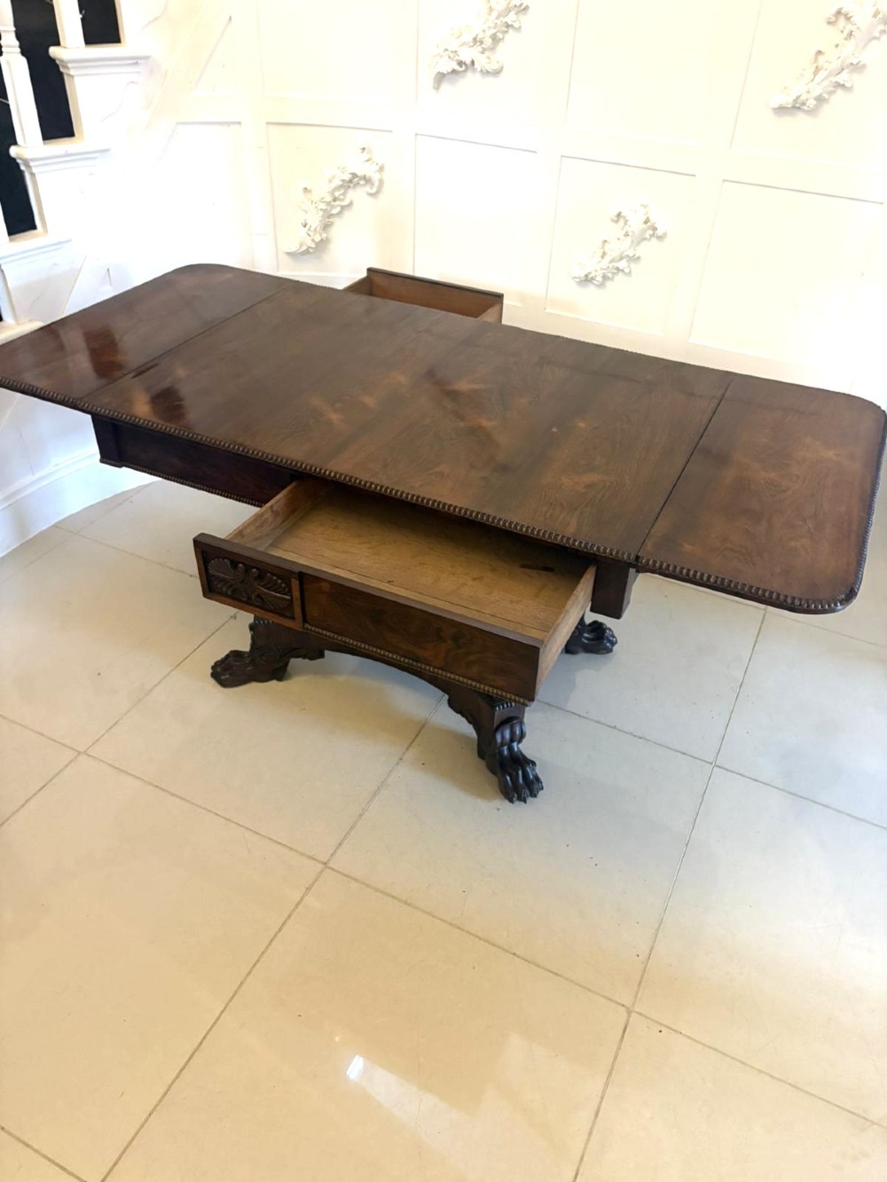 A Regency dark rosewood drop-leaf sofa table with a turned pedestal base and carved claw feet. View II