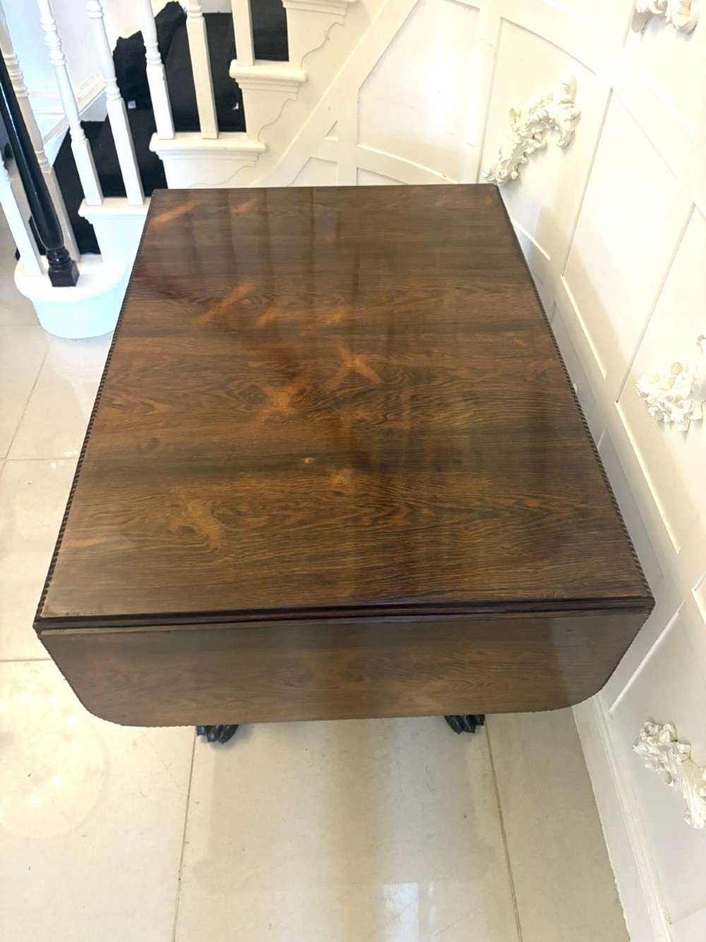 A Regency dark rosewood drop-leaf sofa table with a turned pedestal base and carved claw feet. View IX