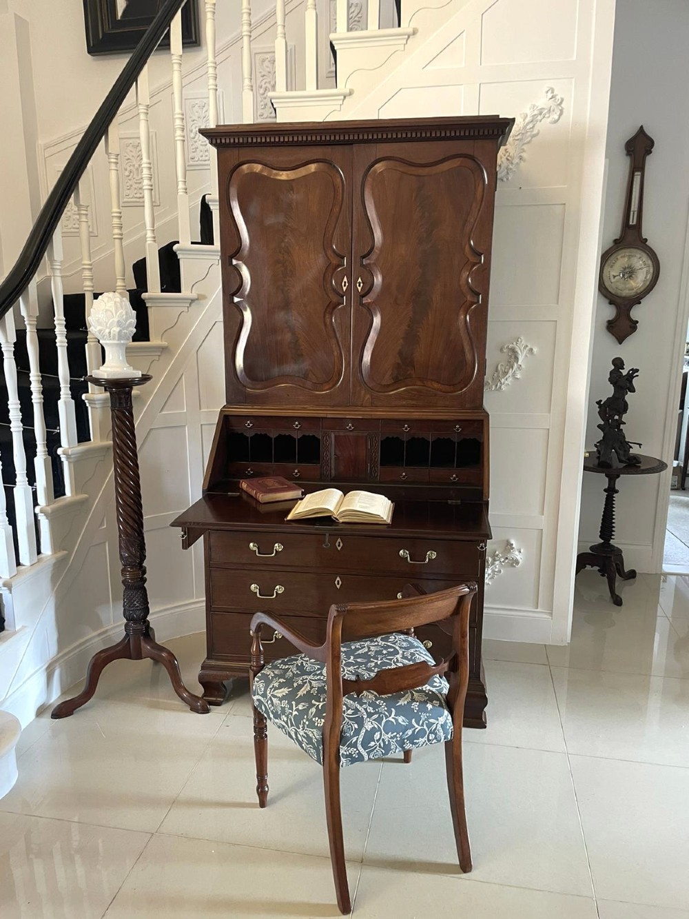 A George II figured mahogany bureau bookcase featuring shaped panel upper doors above a slant-front writing slope and four graduated drawers on bracket feet. View V