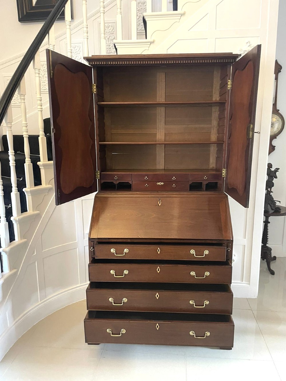 A George II figured mahogany bureau bookcase featuring shaped panel upper doors above a slant-front writing slope and four graduated drawers on bracket feet. View VII