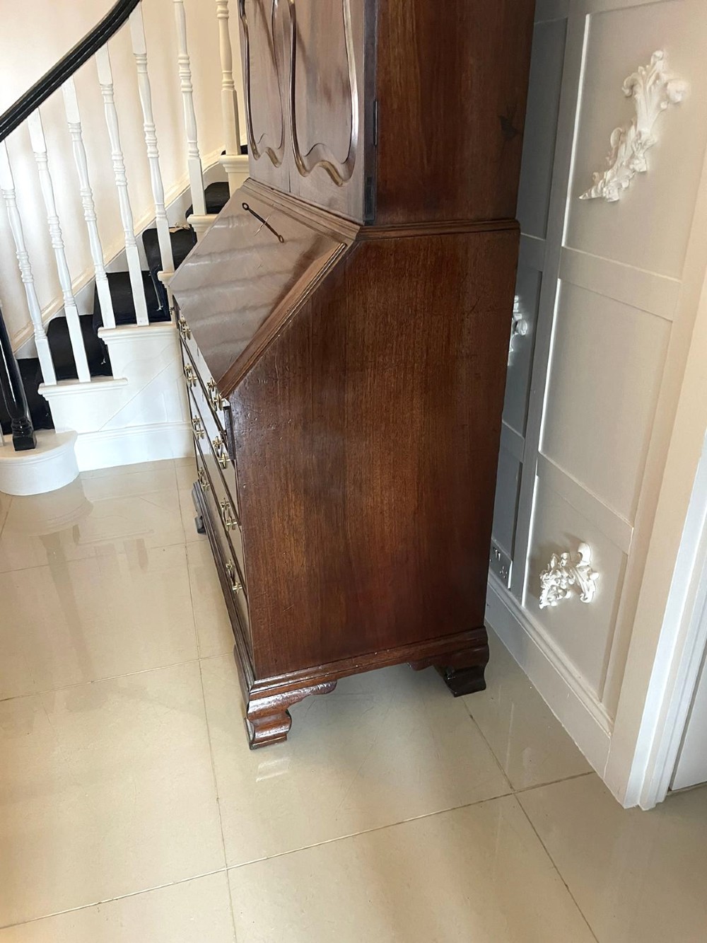 A George II figured mahogany bureau bookcase featuring shaped panel upper doors above a slant-front writing slope and four graduated drawers on bracket feet. View VIII