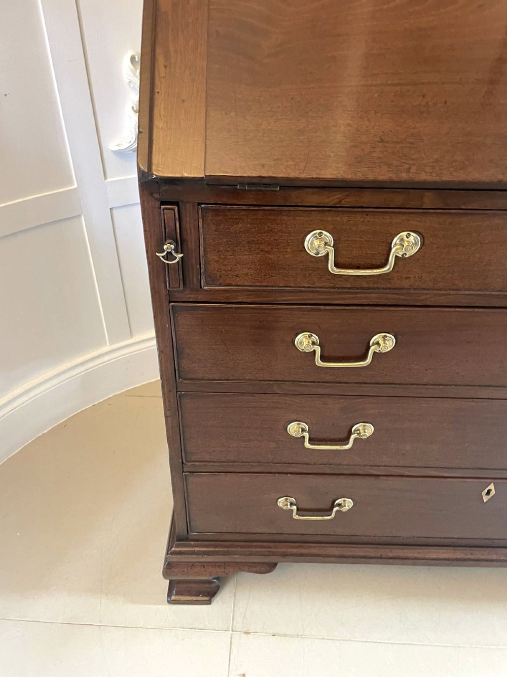 A George II figured mahogany bureau bookcase featuring shaped panel upper doors above a slant-front writing slope and four graduated drawers on bracket feet. View XII