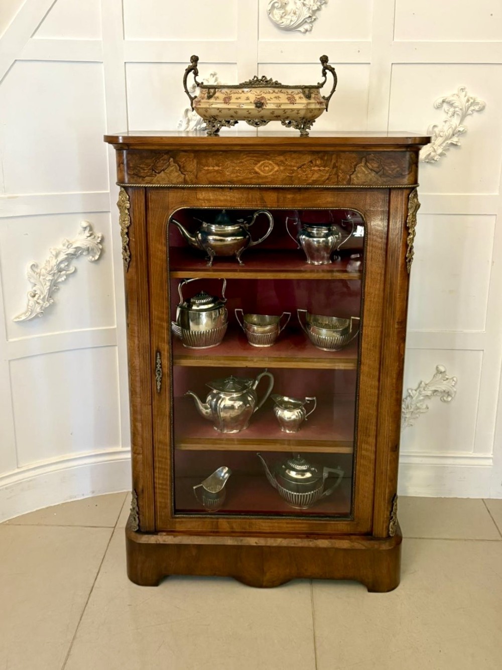 A Victorian burr walnut pier cabinet featuring a single glazed door, floral marquetry along the frieze, and gilt ormolu corner mounts. View III