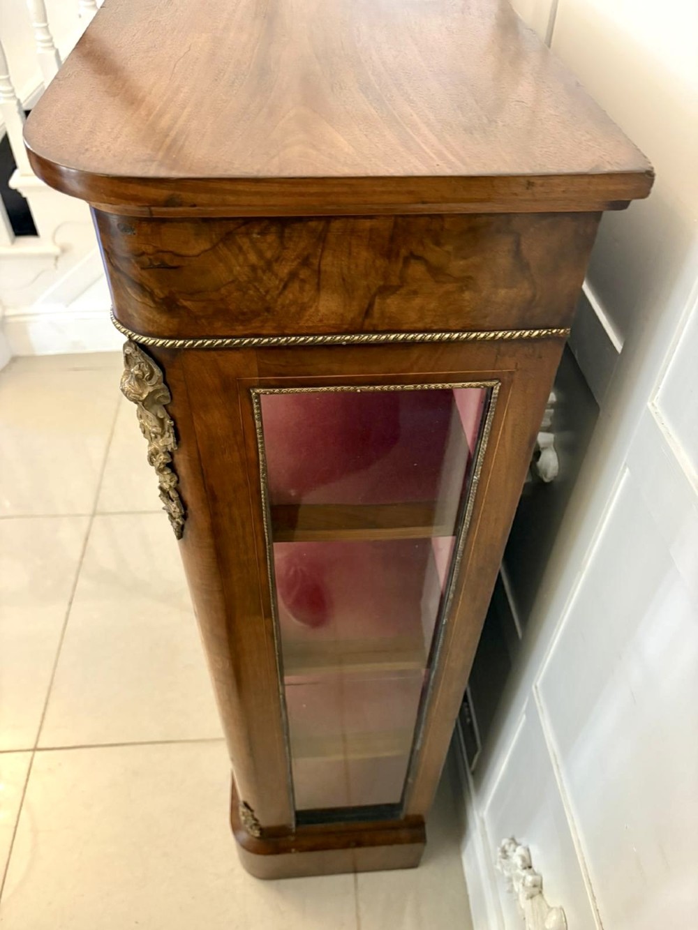 A Victorian burr walnut pier cabinet featuring a single glazed door, floral marquetry along the frieze, and gilt ormolu corner mounts. View IV