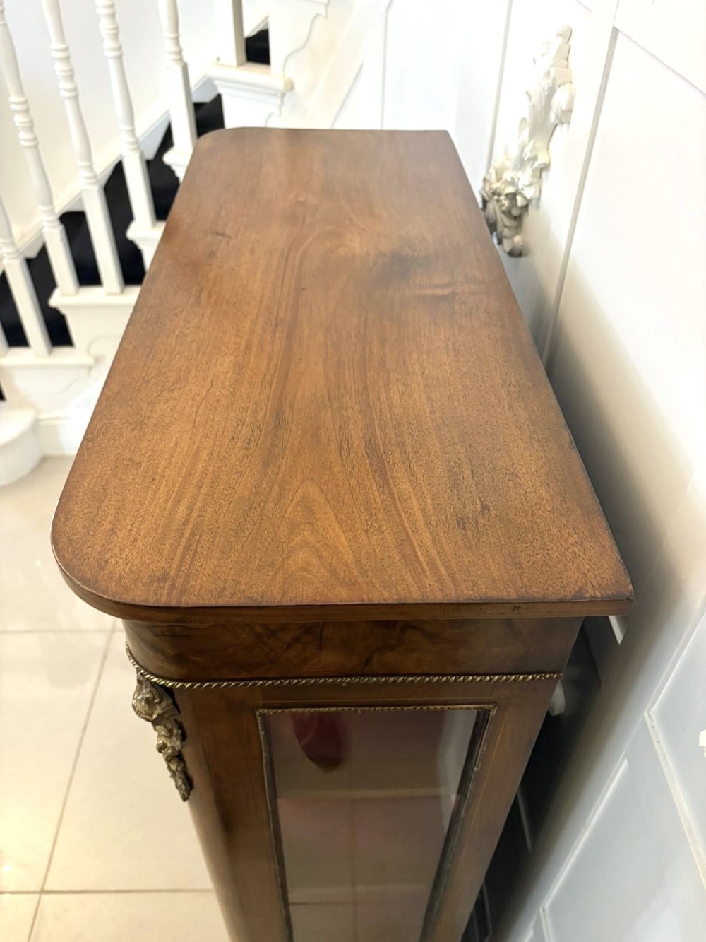 A Victorian burr walnut pier cabinet featuring a single glazed door, floral marquetry along the frieze, and gilt ormolu corner mounts. View V