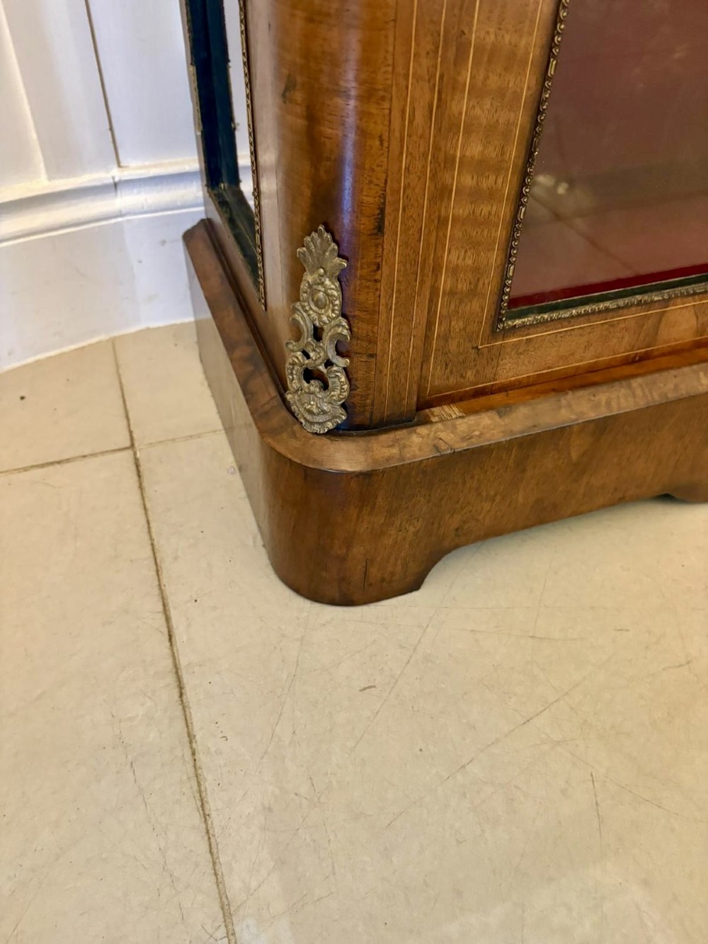 A Victorian burr walnut pier cabinet featuring a single glazed door, floral marquetry along the frieze, and gilt ormolu corner mounts. View VII