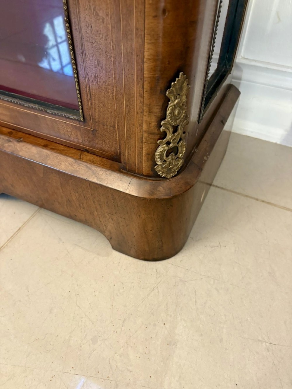 A Victorian burr walnut pier cabinet featuring a single glazed door, floral marquetry along the frieze, and gilt ormolu corner mounts. View X