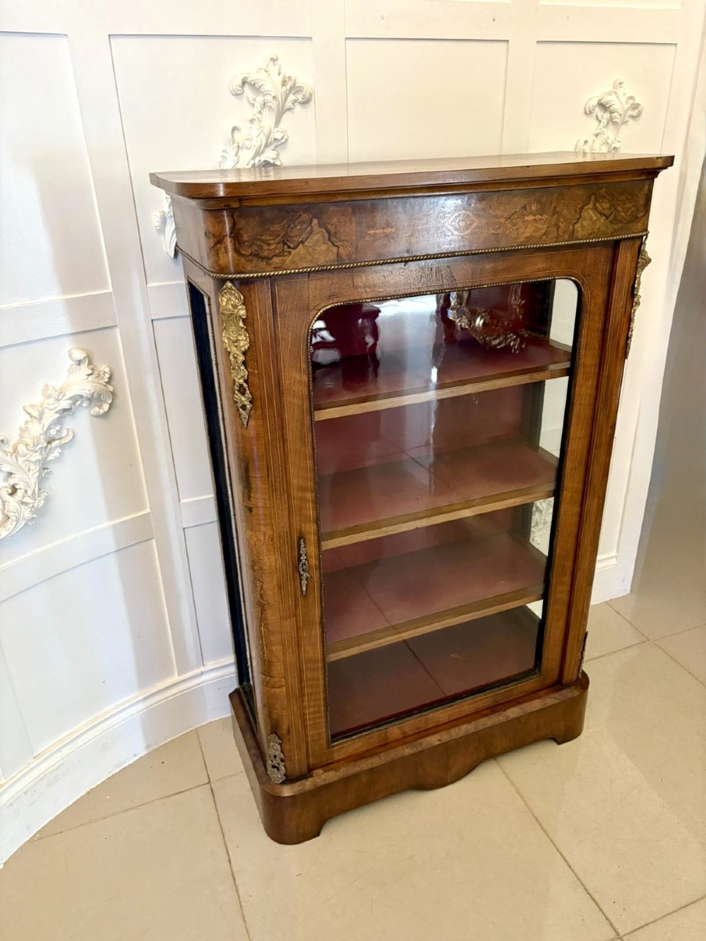 A Victorian burr walnut pier cabinet featuring a single glazed door, floral marquetry along the frieze, and gilt ormolu corner mounts. View XII