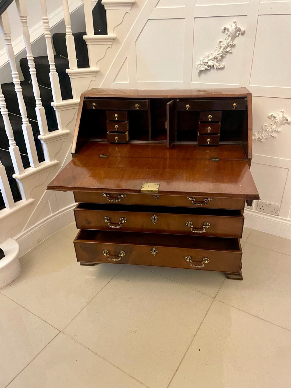 An 18th-century George III mahogany bureau featuring a slant front writing slope above four graduated drawers with brass handles on bracket feet. View V