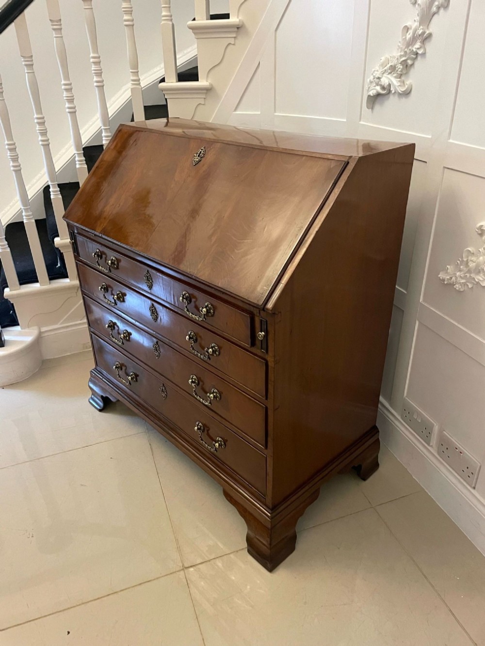 An 18th-century George III mahogany bureau featuring a slant front writing slope above four graduated drawers with brass handles on bracket feet. View XI