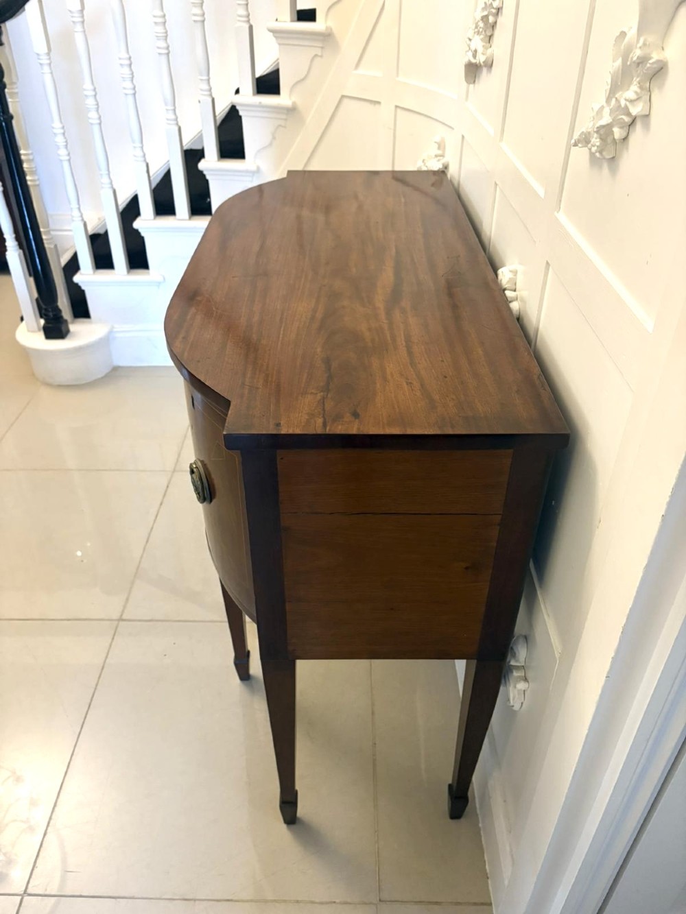A George III mahogany sideboard featuring geometric boxwood stringing inlay, brass rosette handles, a central arch drawer, and square tapered legs. View VII