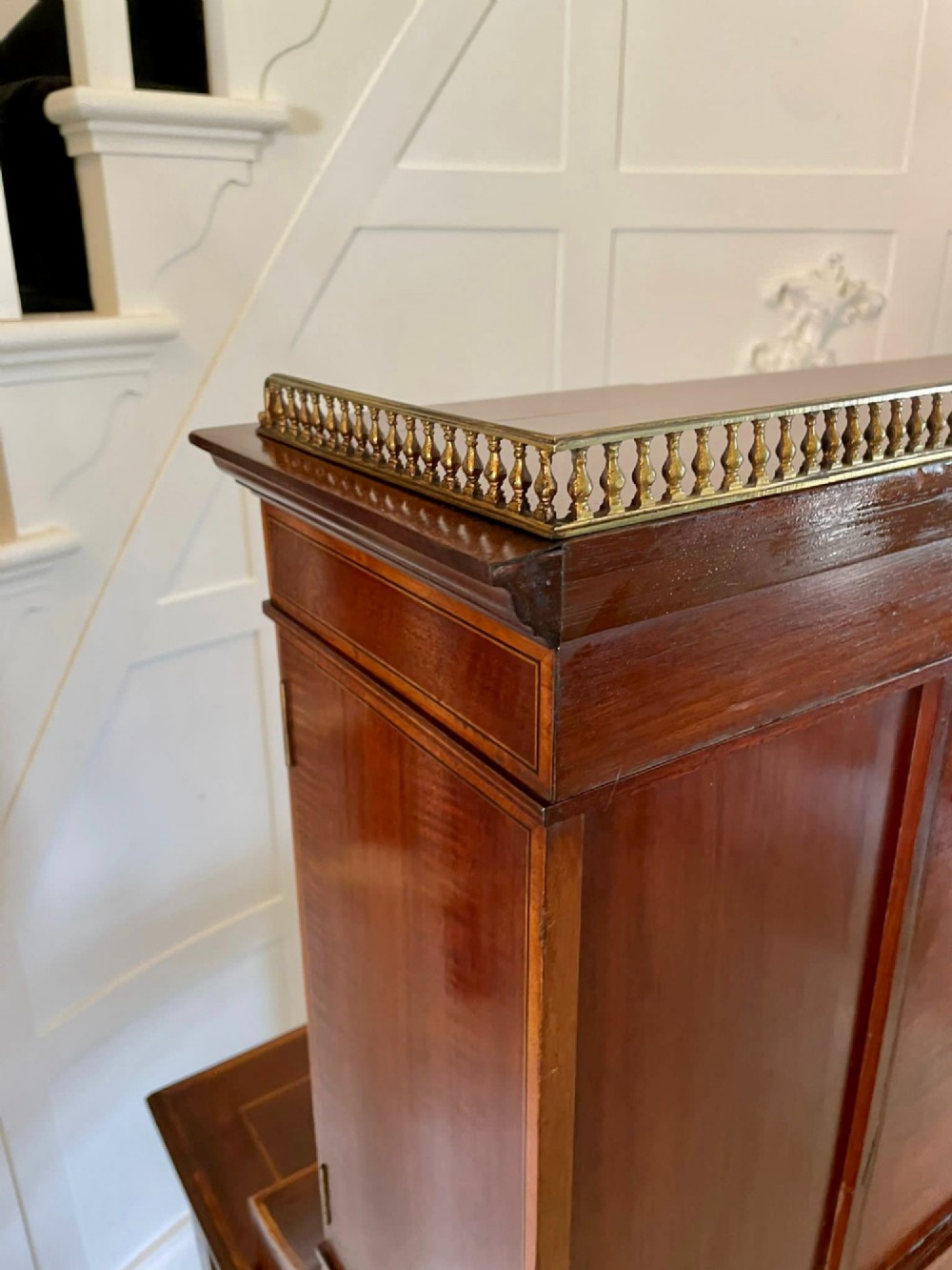 A Victorian inlaid mahogany writing desk featuring a brass gallery top, mirrored arched niche, floral marquetry cabinets, small drawers, and tapered square legs. View VII