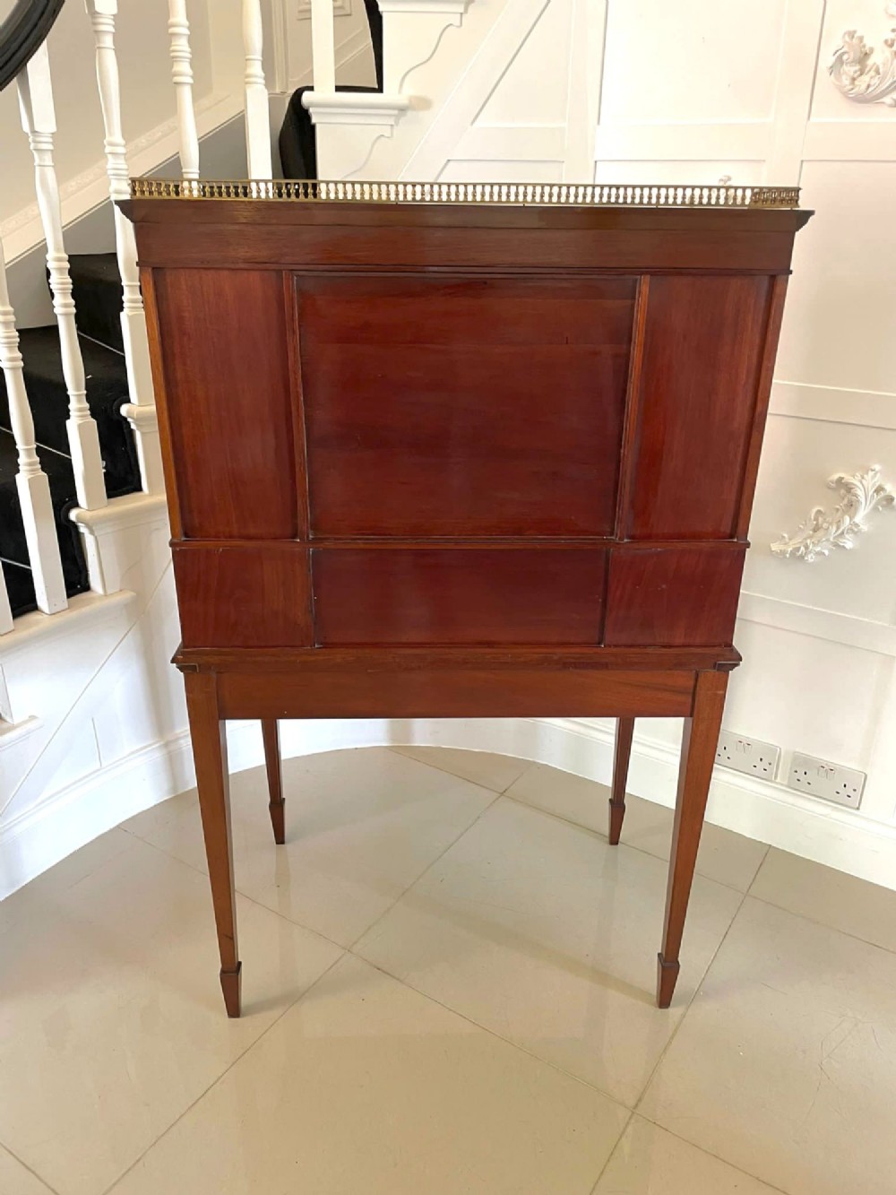 A Victorian inlaid mahogany writing desk featuring a brass gallery top, mirrored arched niche, floral marquetry cabinets, small drawers, and tapered square legs. View VIII