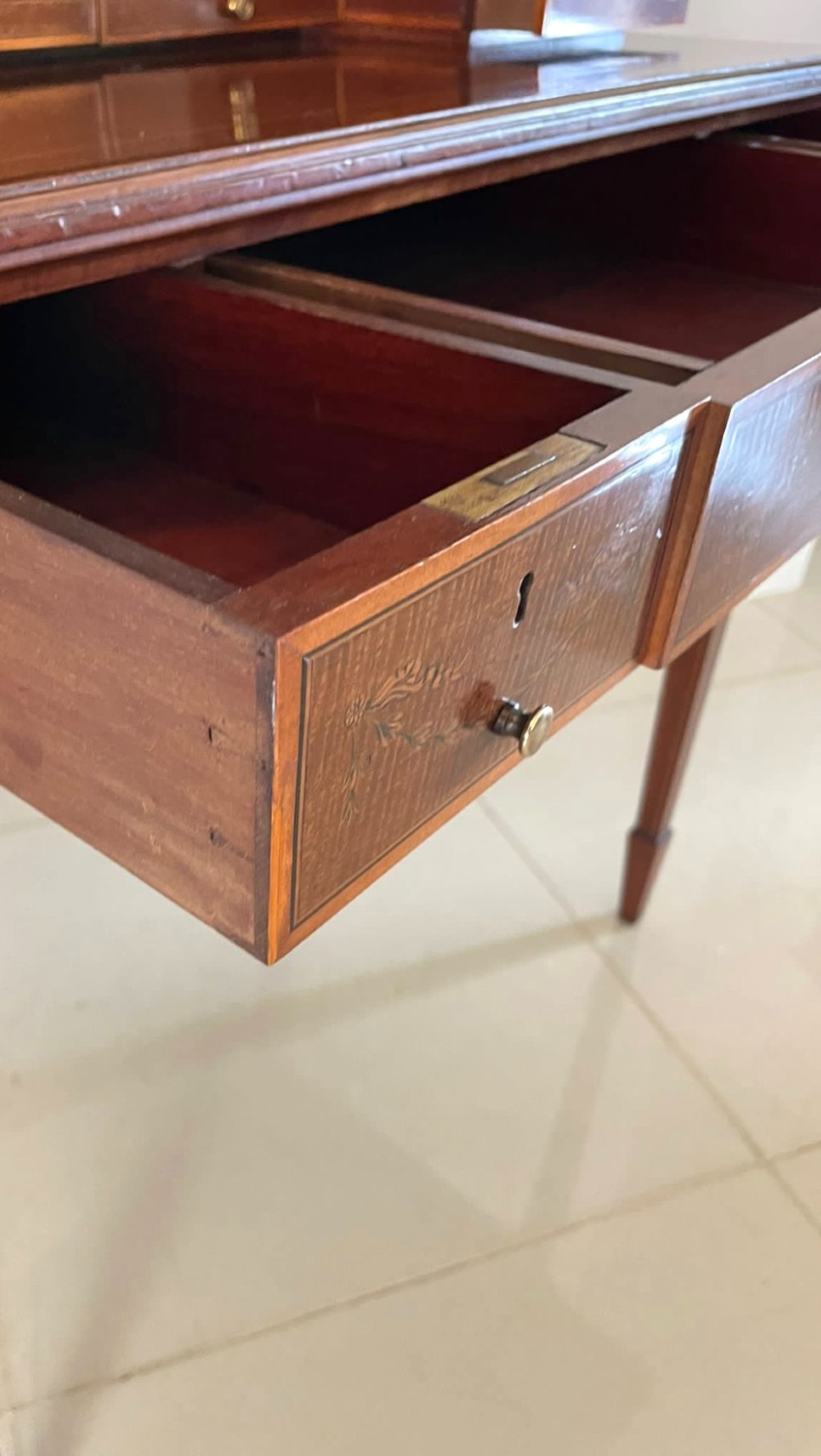 A Victorian inlaid mahogany writing desk featuring a brass gallery top, mirrored arched niche, floral marquetry cabinets, small drawers, and tapered square legs. View IX