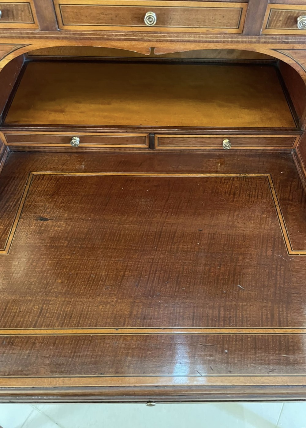 A Victorian inlaid mahogany writing desk featuring a brass gallery top, mirrored arched niche, floral marquetry cabinets, small drawers, and tapered square legs. View X