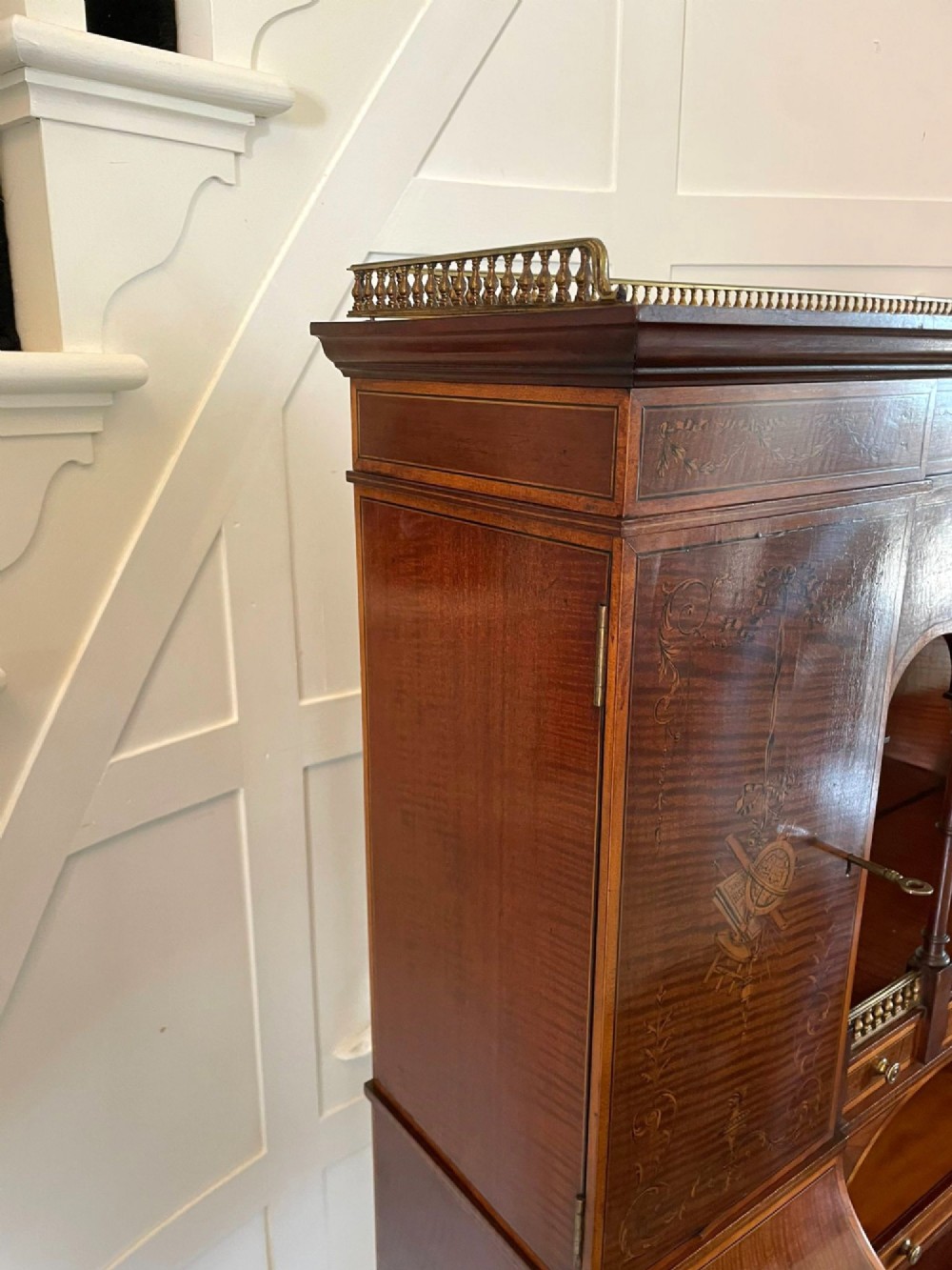 A Victorian inlaid mahogany writing desk featuring a brass gallery top, mirrored arched niche, floral marquetry cabinets, small drawers, and tapered square legs. View XIII