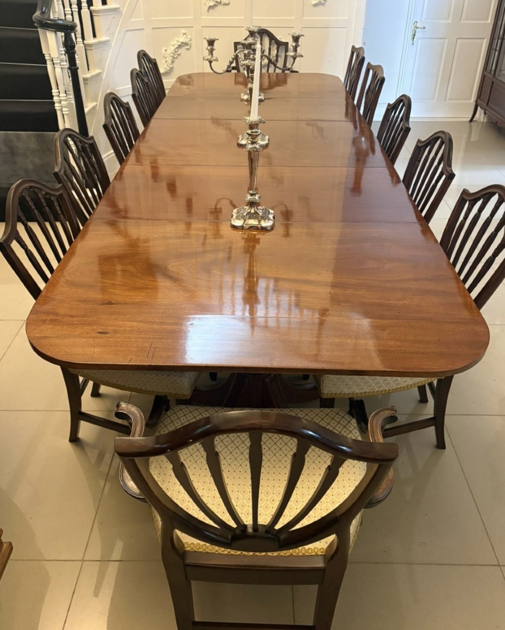A large Georgian extending dining table crafted from polished figured mahogany with a three-pillar tripod pedestal base and brass castors. View V