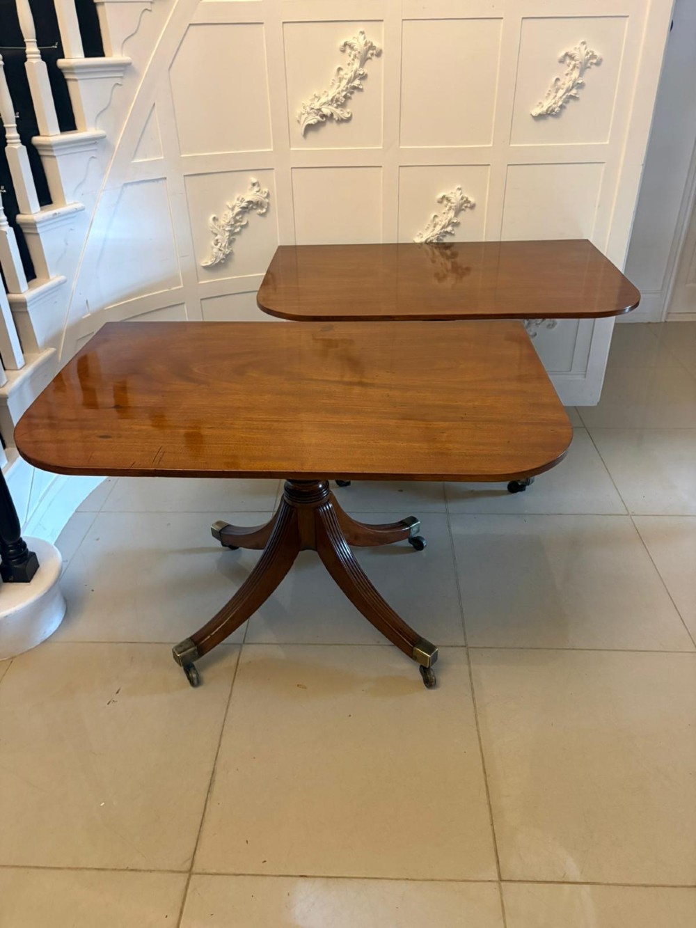 A large Georgian extending dining table crafted from polished figured mahogany with a three-pillar tripod pedestal base and brass castors. View VII