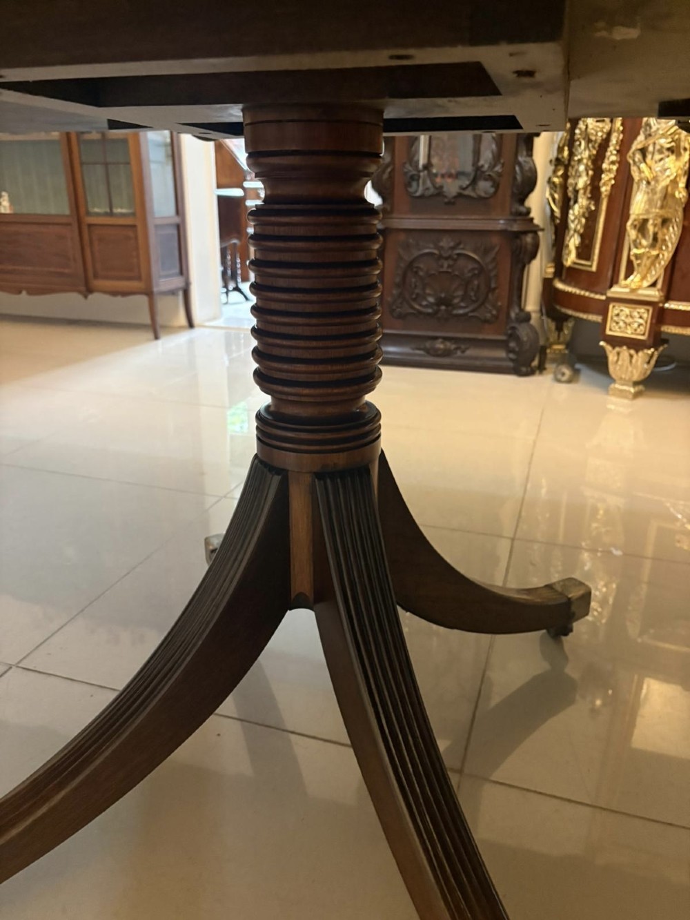 A large Georgian extending dining table crafted from polished figured mahogany with a three-pillar tripod pedestal base and brass castors. View IX