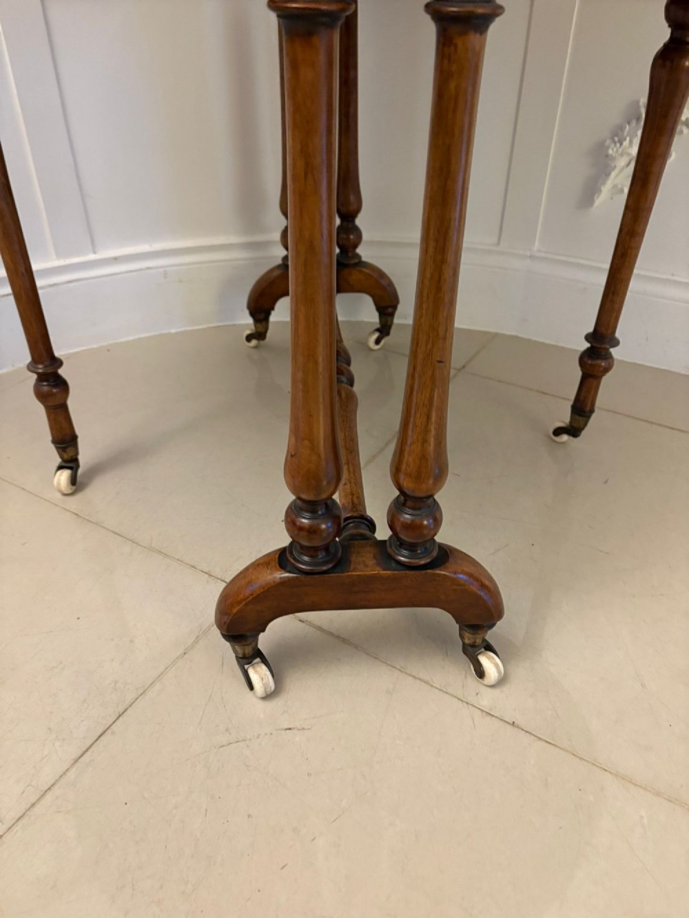A folded Victorian burr walnut Sutherland table featuring turned upright supports, a stretcher base, and white ceramic castors. View II