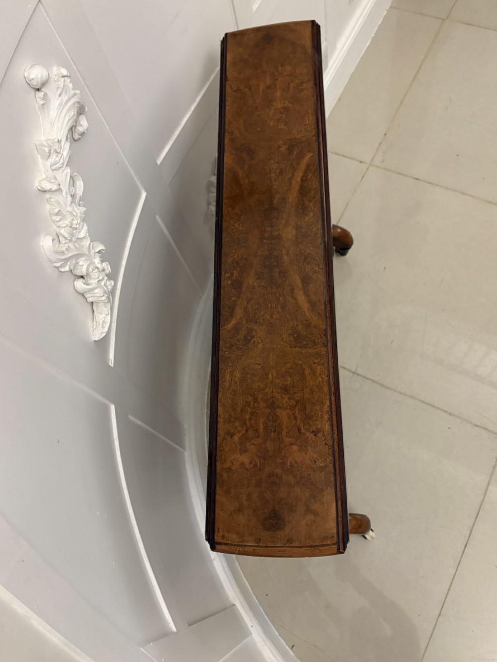 A folded Victorian burr walnut Sutherland table featuring turned upright supports, a stretcher base, and white ceramic castors. View XI