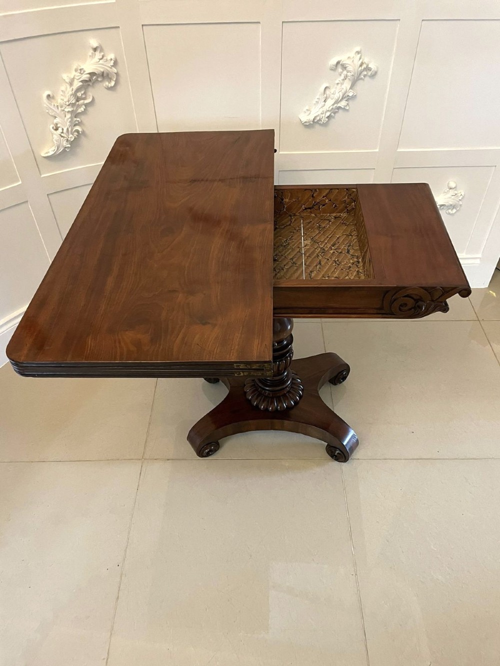 A William IV mahogany fold-over tea table with a turned gadrooned pedestal stem and a concave quadform base ending in scroll feet. View IV